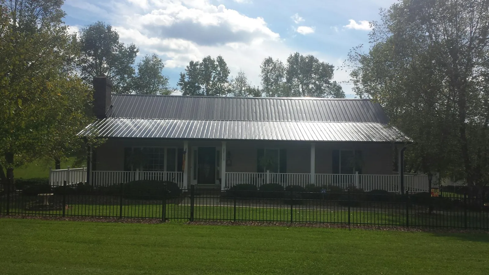 Gray metal roof on a brick ranch with a full width front porch — Gutter Guard Installation work by our crew in Creal Springs