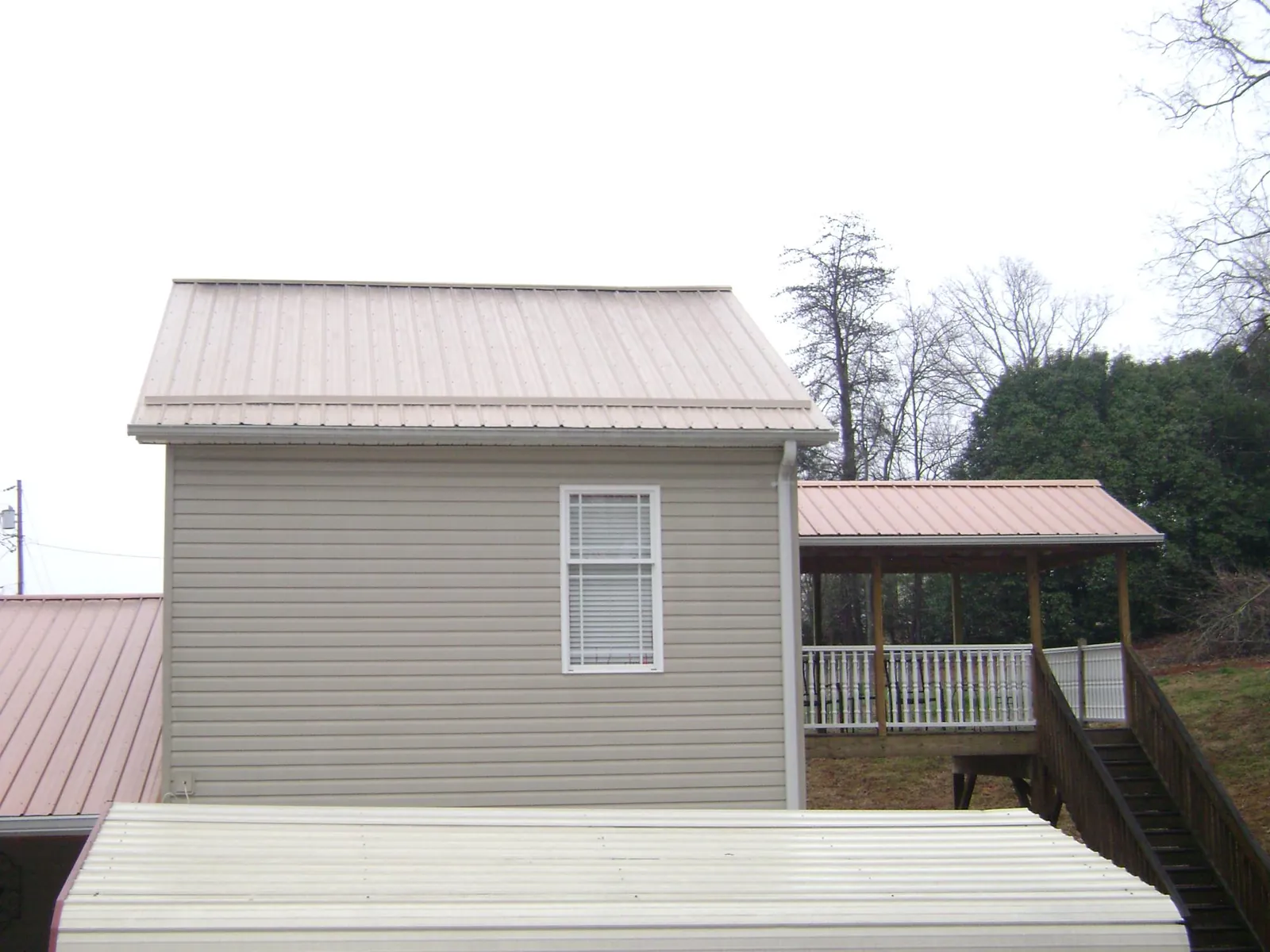 Tan metal roofs on a two story addition and attached porch, from a Roof Replacement job in Creal Springs