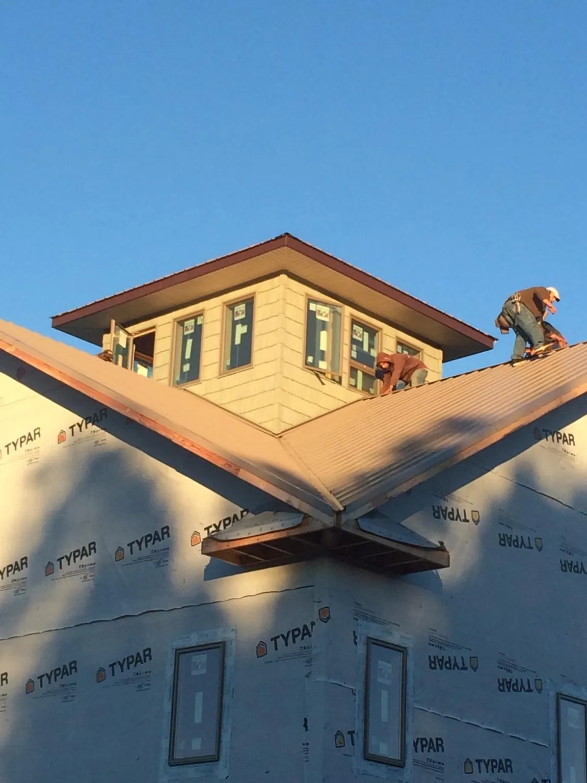 Roofers working around a rooftop cupola on a new metal roof at sunset — Roof Waterproofing in Creal Springs by Roofing Brothers